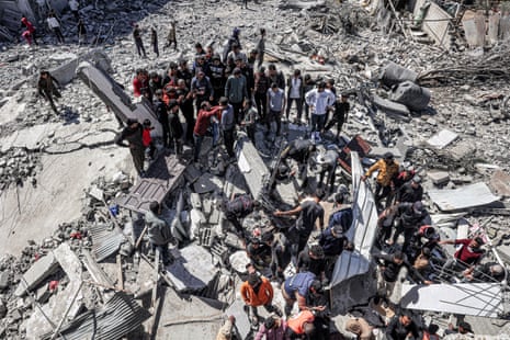 People and first responders inspect the rubble and debris of a building that collapsed after an Israeli airstrike in the Rafah refugee camp in the southern Gaza Strip on Wednesday.