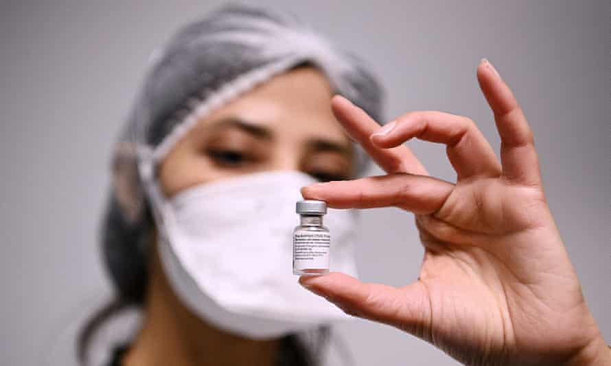 health worker with vial of Pfizer vaccine