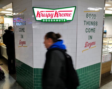 a women walking by a Krispy Kreme doughnut outpost