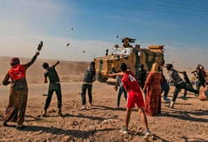 Syrians throw stones towards Turkish military vehicles during a Turkish-Russian army patrol near the town of Darbasiyah along the border between Syria and Turkey.