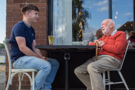 Two men sitting opposite each other at a table outside a restaurant