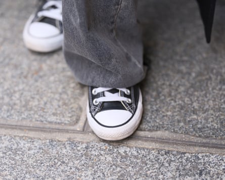 A close up of black Converse shoes on a street.