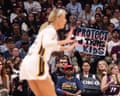 Sophie Cunningham on a basketball court as a fan holds a sign reading "Protect Trans Kids"