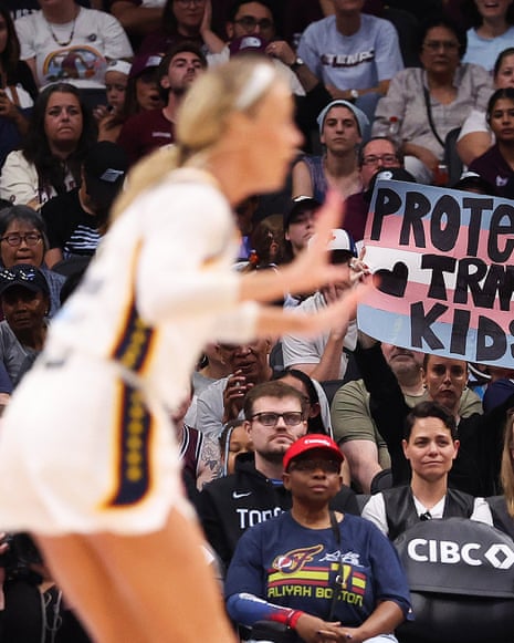 Sophie Cunningham on a basketball court as a fan holds a sign reading "Protect Trans Kids"