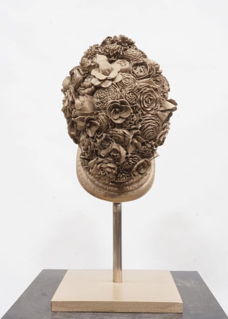 A sculpture of a beige fencing mask covered in flowers
