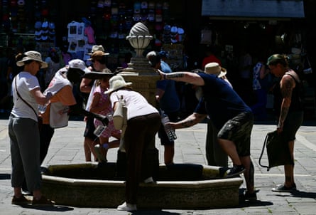 People fill bottles from a public water fountain in Venice