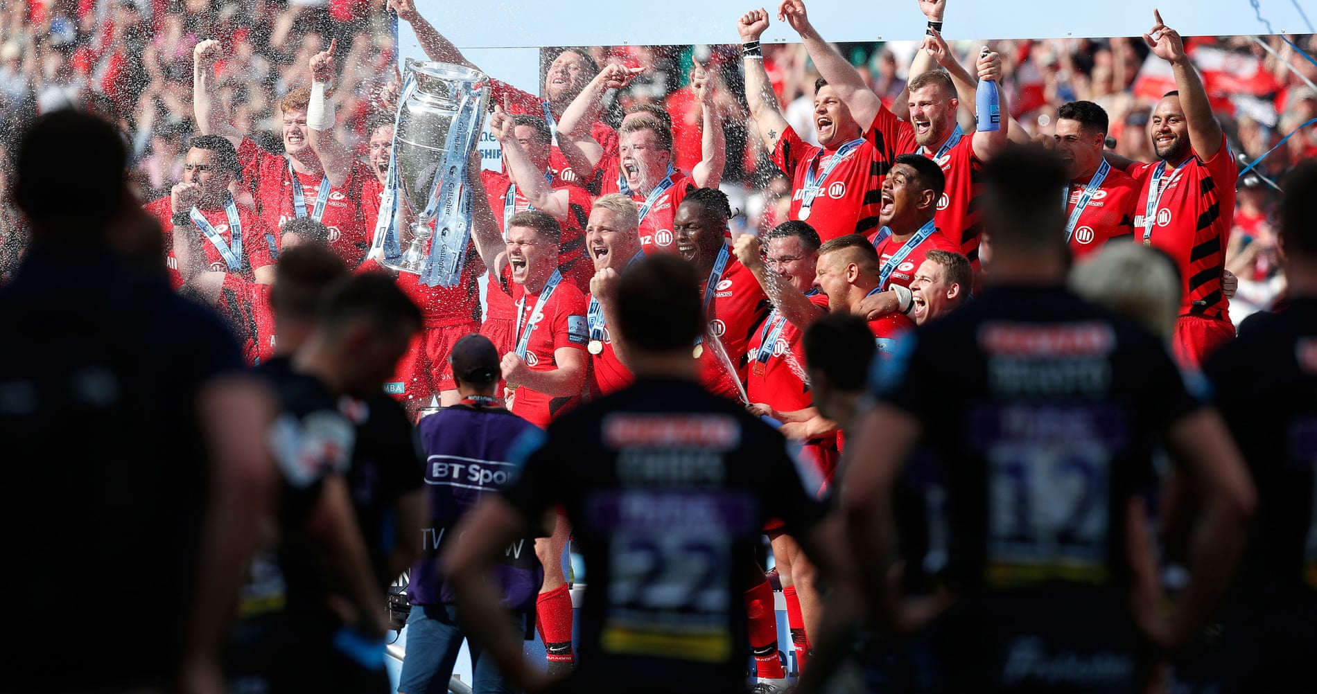 Exeter players look on as Owen Farrell lifts the trophy as he and his Saracens teammates celebrate beating Exeter 37–34 in the Premiership final in June 2019