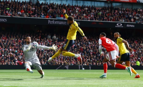 Arsenal goalkeeper David Raya dives to save as Leeds United's Jayden Bogle leaps and volleys.
