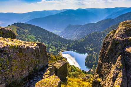 View over a small lake from rocky pinnacles in forested rounded mountains in France