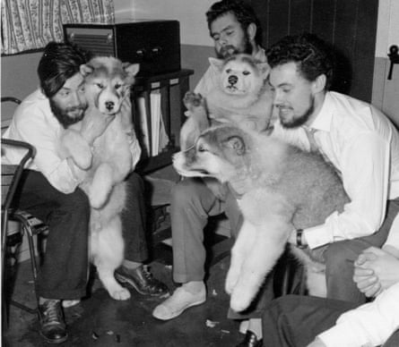 A black-and-white image of three men holding dogs