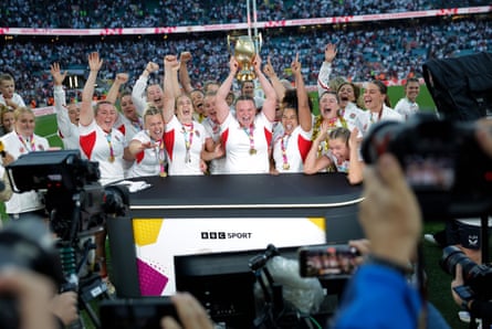 The victorious England team, led by prop Sarah Bern with the trophy, storm the BBC pitchside studio with the trophy.