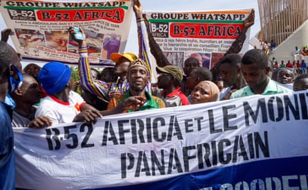 Protesters waving placards march in the street behind a banner saying ‘B-52 Africa’ calling for co-operation between Niger and Russia, and with photos of mutilated bodies
