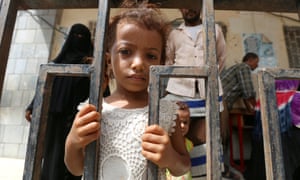 A girl stands behind a fence at a school to which she and her family have been evacuated amid the fighting in Hodeida.