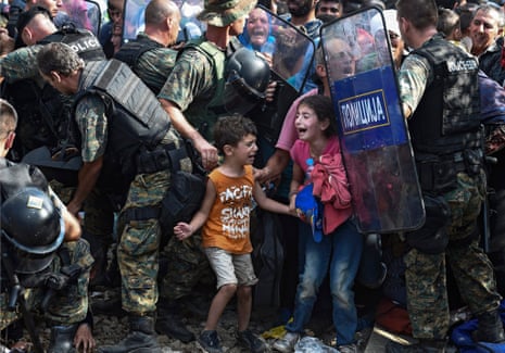 Children cry as migrants waiting on the Greek side of the border break through a cordon of Macedonian special police forces