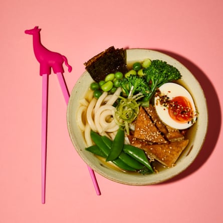 Kids' chopsticks with giraffe on top, alongside plate of food
