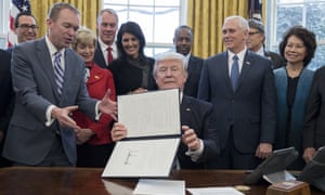 President Donald Trump signs an executive order in the Oval Office.