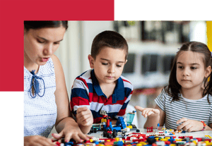 Young female teacher sitting with group of preschool kids and playing with plastic blocks together in classroom of preschool building