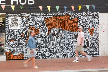 People walk past a colourful mural that says 'Tamika was here'