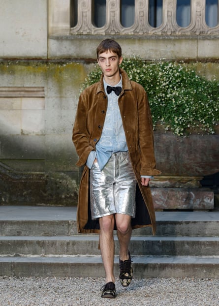 Model in an overcoat worn with metallic shorts and a bow tie