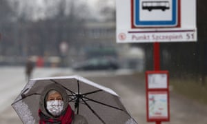 زنی با ماسک صورت از کنار ایستگاه موقت بیماران واکسیناسیون Covid در ورشو ، لهستان عبور می کند.