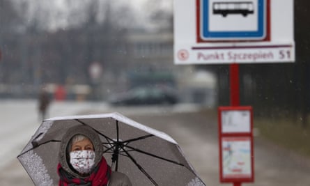 A woman wearing a face mask walks past a temporary bus stop for Covid vaccination patients in Warsaw, Poland.