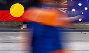 A person walks past the Aboriginal and Australian flags