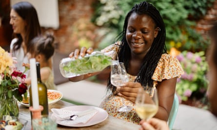 A woman pours water into her glass at a garden table of revellers