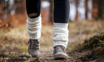 Woman walking on footpath in forest. Knitted leg warmers on hiking boot