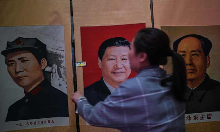 A stall vendor holding a portrait of Xi Jinping next to pictures of the former Chinese leader Mao Zedong at Dongfanghong theatre in Yan’an.