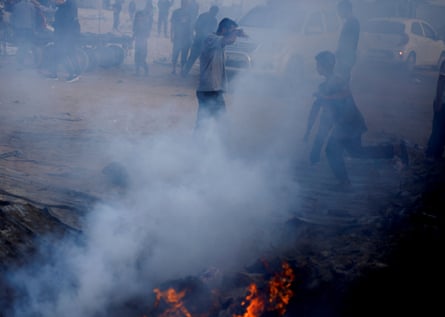 Palestinians walk past smoke rising from a fire