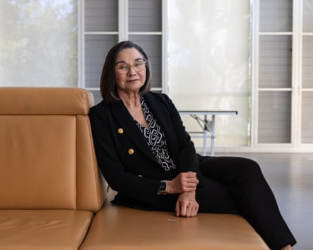 Kate in a suit sitting on a brown leather sofa