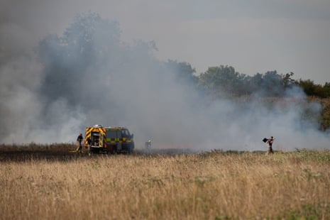 A fire engine near a smoky field fire.