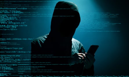 Hacker in the dark wearing a hoodie using a phone, a blue screen with coding on it as backdrop