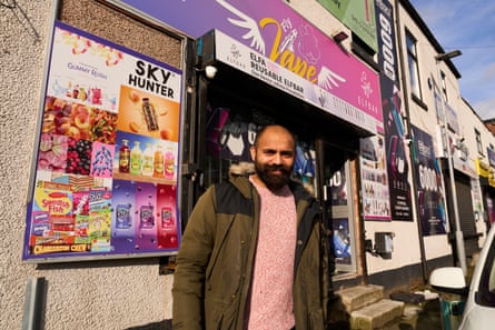 A man standing in front of a shop with a purple sign saying Fly Vape and with angel wings either side of the words