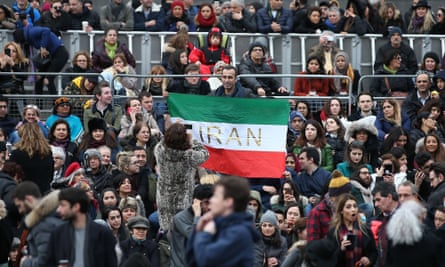 A man holds up an Iranian flag as people gather in Trafalgar Square for the public screening of The Salesman.