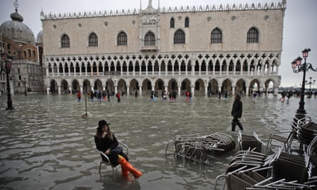 A woman sits in a flooded St. Mark’s Square.