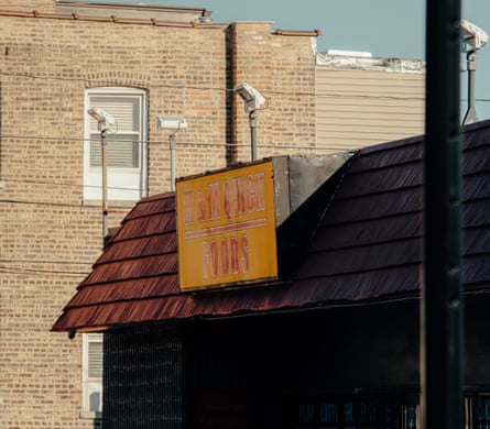 The yellow sign of the store with red writing on, attached to the roof of a building