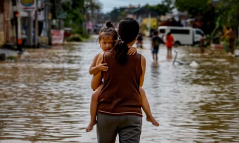 A woman carries her child through flood water