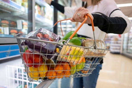 A woman holds a basket of goods in a supermarket