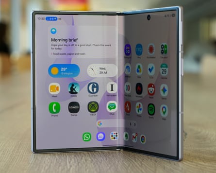 The Samsung Galaxy Z Fold 8 stood up on a wooden table while partly folded showing a the home screen on the internal flexible display.