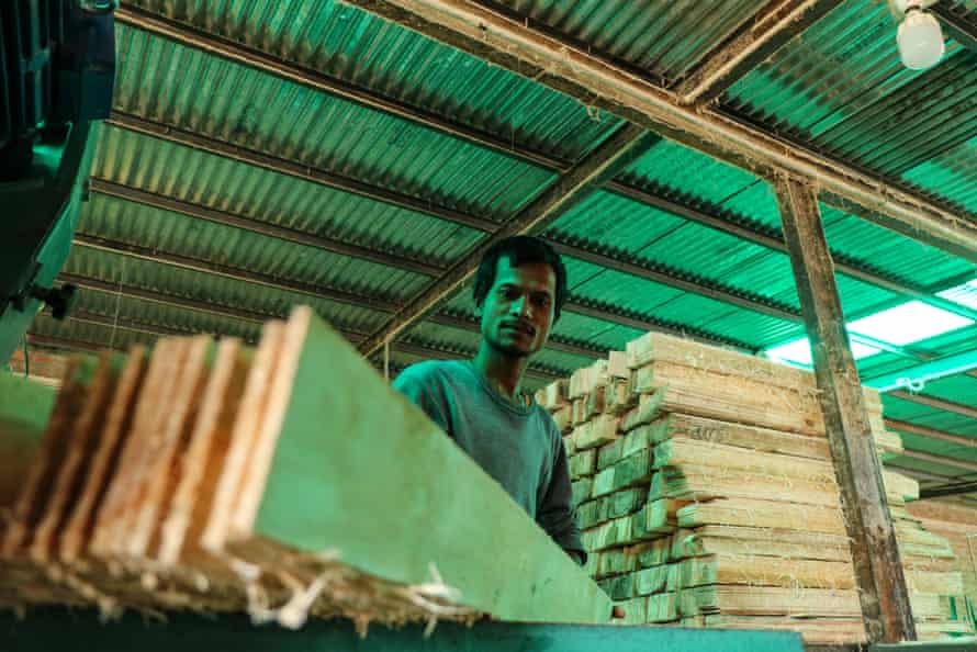 A migrant worker trims a plank of poplar wood at a pencil slate factory