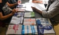 People sit at a table covered in ballot papers for French political parties