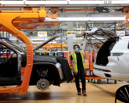 A Stellantis assembly worker walks between two Jeep Grand Cherokees on an assembly line