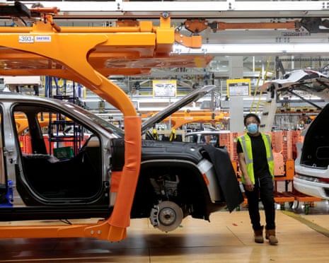 A Stellantis assembly worker walks between two 2021 Jeep Grand Cherokee L vehicles on the assembly line at the Detroit Assembly Complex in Michigan in 2021.
