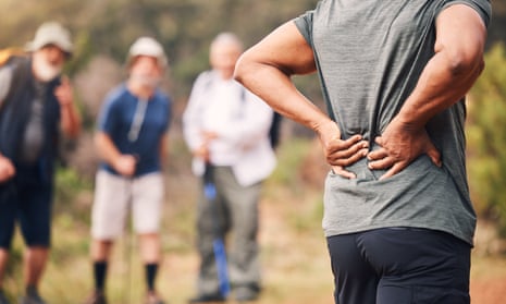 Man with back pain as people in background look on
