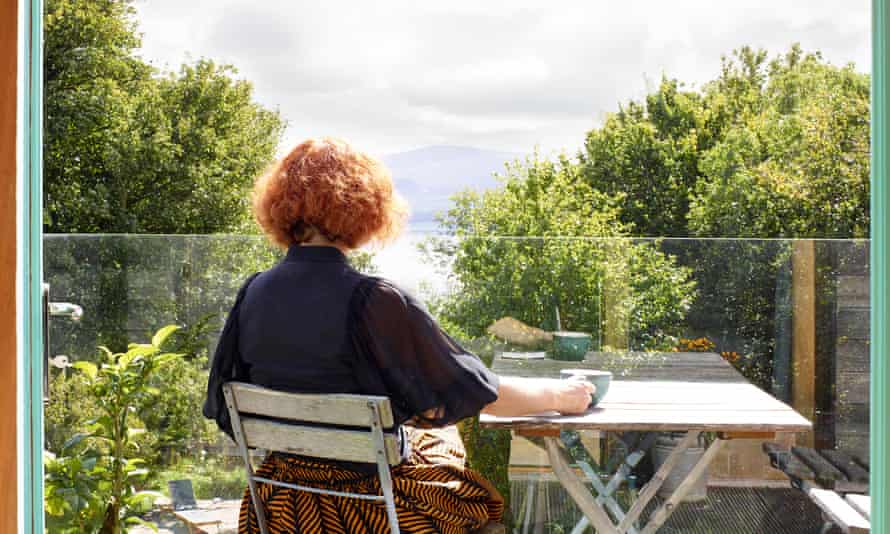 Rear view of Mairead sitting on the balcony with a coffee and the view ahead of her