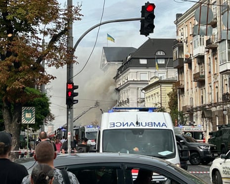 Onlookers watch as Ukrainian rescue personnel work to extinguish a fire in the headquarters of the Security Service of Ukraine (SBU) following an air attack in Kyiv.