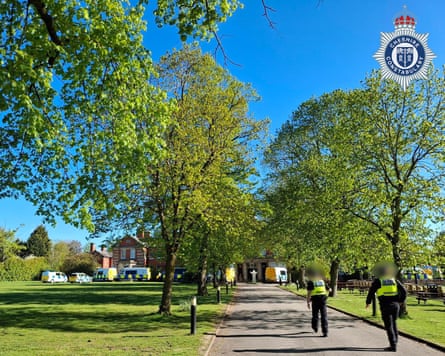 Officers walk along a long tree-lined driveway towards the building