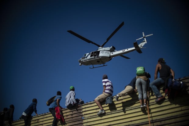 Central American migrants climb the border fence near El Chaparral border crossing in Tijuana
