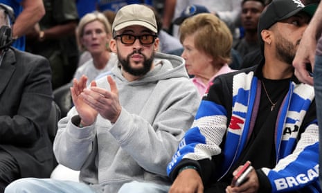 Puerto Rican recording artist Bad Bunny, left, sits courtside during the first half of an NBA playoff game last month in Dallas.